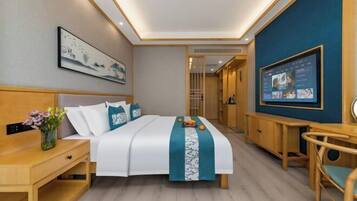 Una habitación de hotel con cama, mesita de noche, televisor y escritorio.