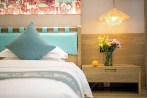 Habitación de hotel con cama, mesita de noche con un florero y una lámpara de pared.