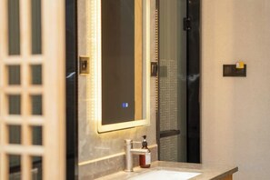 Un baño con un espejo grande, un lavabo y un perchero para toallas.