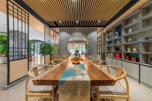 Una larga mesa de madera con sillas, rodeada de estanterías con adornos.