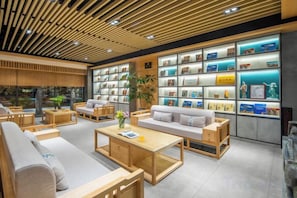 Et moderne loungeområde med sofaer, borde og en reol fyldt med bøger.