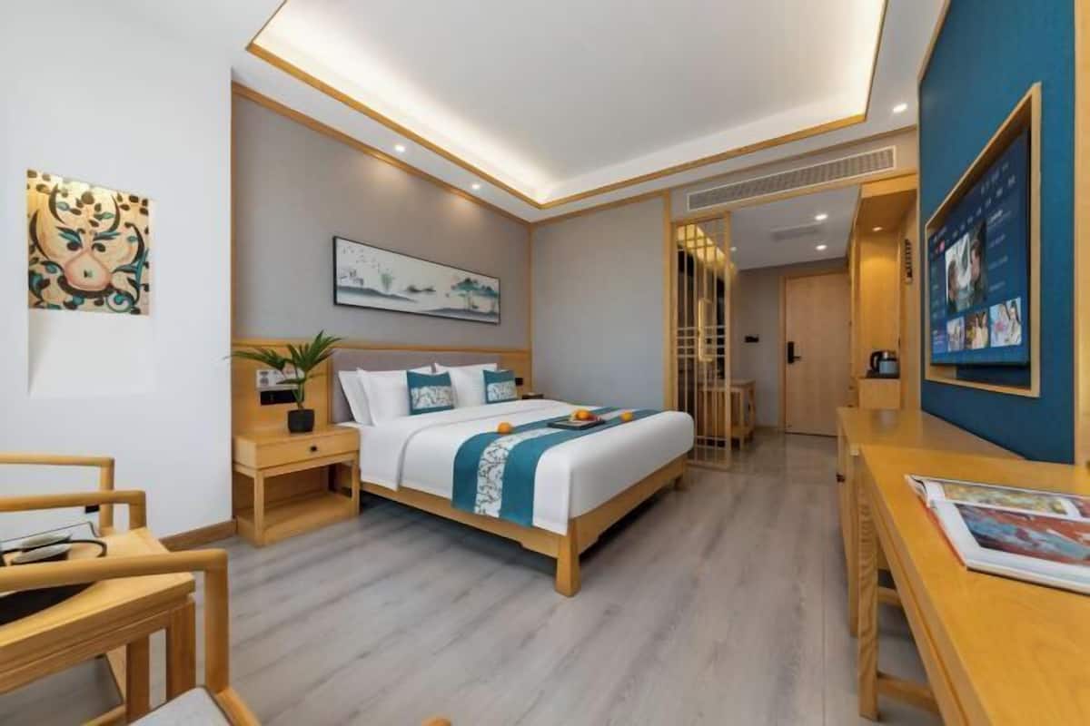 Ein modernes Hotelzimmer mit Bett, Nachttischen, Schreibtisch und Fernseher.