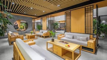 A modern interior with a seating area, a round mirror, and a wooden ceiling.