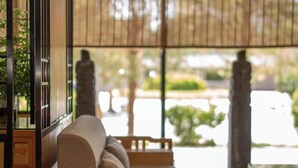 A room with a wooden sofa, a tatami mat, and a view of the outdoors.