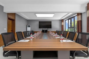 A conference room with a long table, black chairs, and a flat-screen TV. - Huayulou International Hotel (Dunhuang)