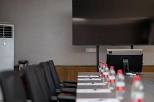 Un salón de conferencias con una larga mesa, sillas, un proyector y un televisor de pantalla plana.