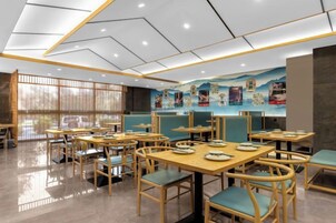 Un restaurante con varias mesas y sillas, un mural en la pared y un diseño de techo moderno.