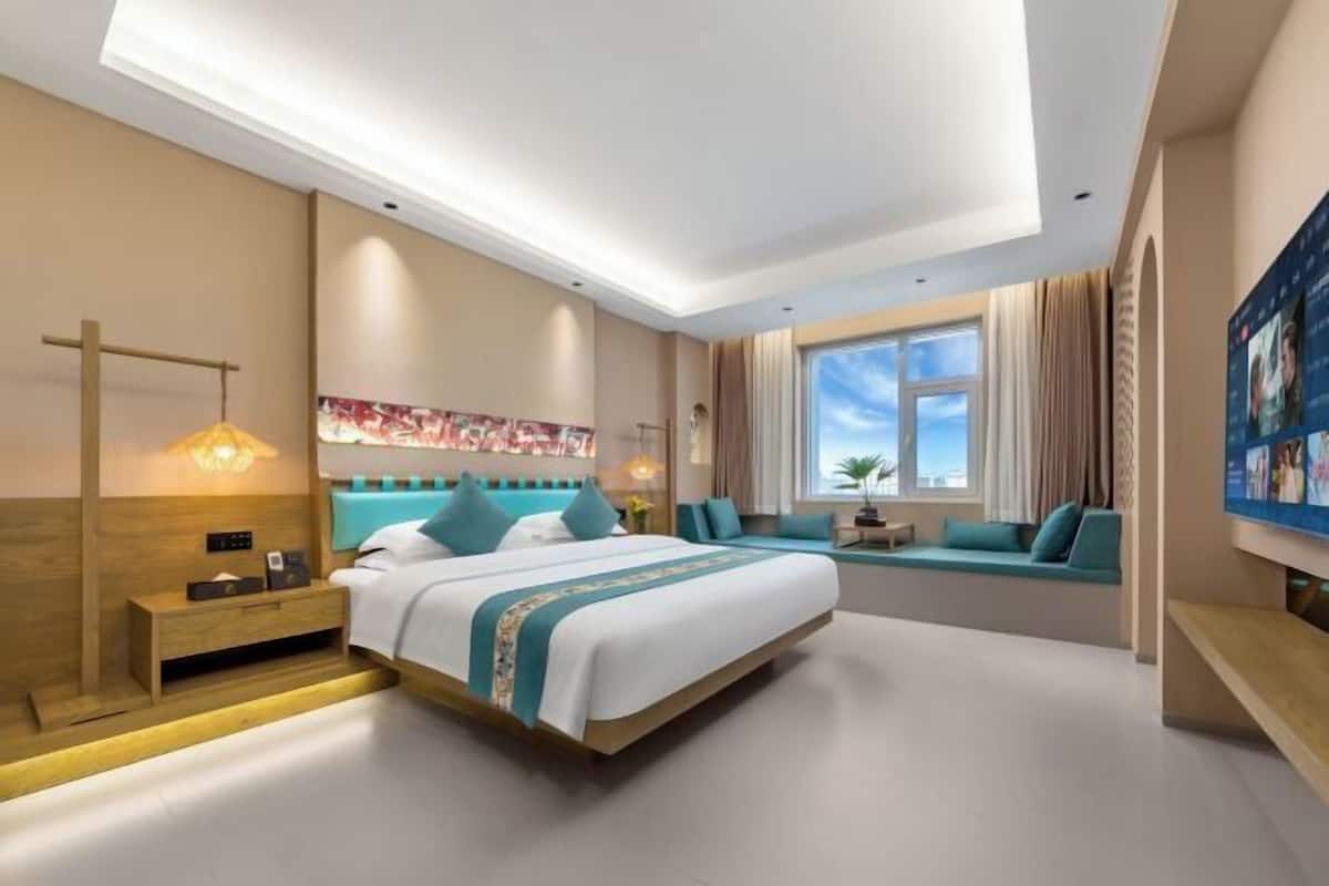 Ein modernes Hotelzimmer mit einem großen Bett, einer Sitzecke mit Blick und einer Deckenleuchte.