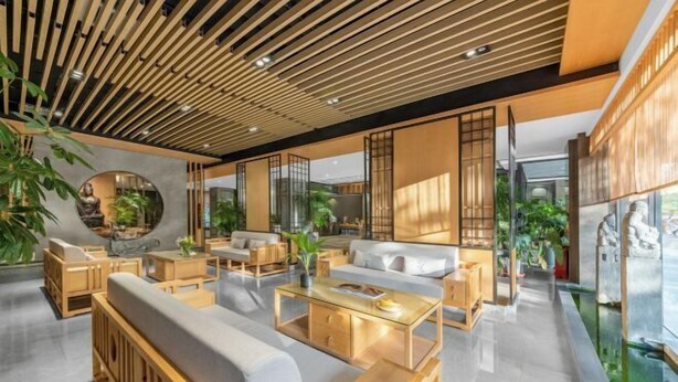 A modern interior with wooden furniture, a round mirror, and a glass partition.