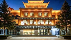 A multi-story hotel with a traditional architectural style, featuring a prominent entrance and a well-lit facade.