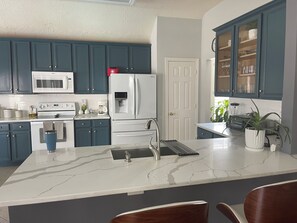 Una cocina moderna con encimera de mármol, electrodomésticos de acero inoxidable y armarios azules.