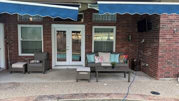 A covered patio area with a pool, outdoor seating, and a brick wall.