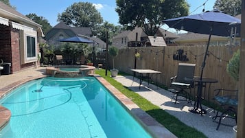 En have med swimmingpool, møbler på terrassen og et træhegn.