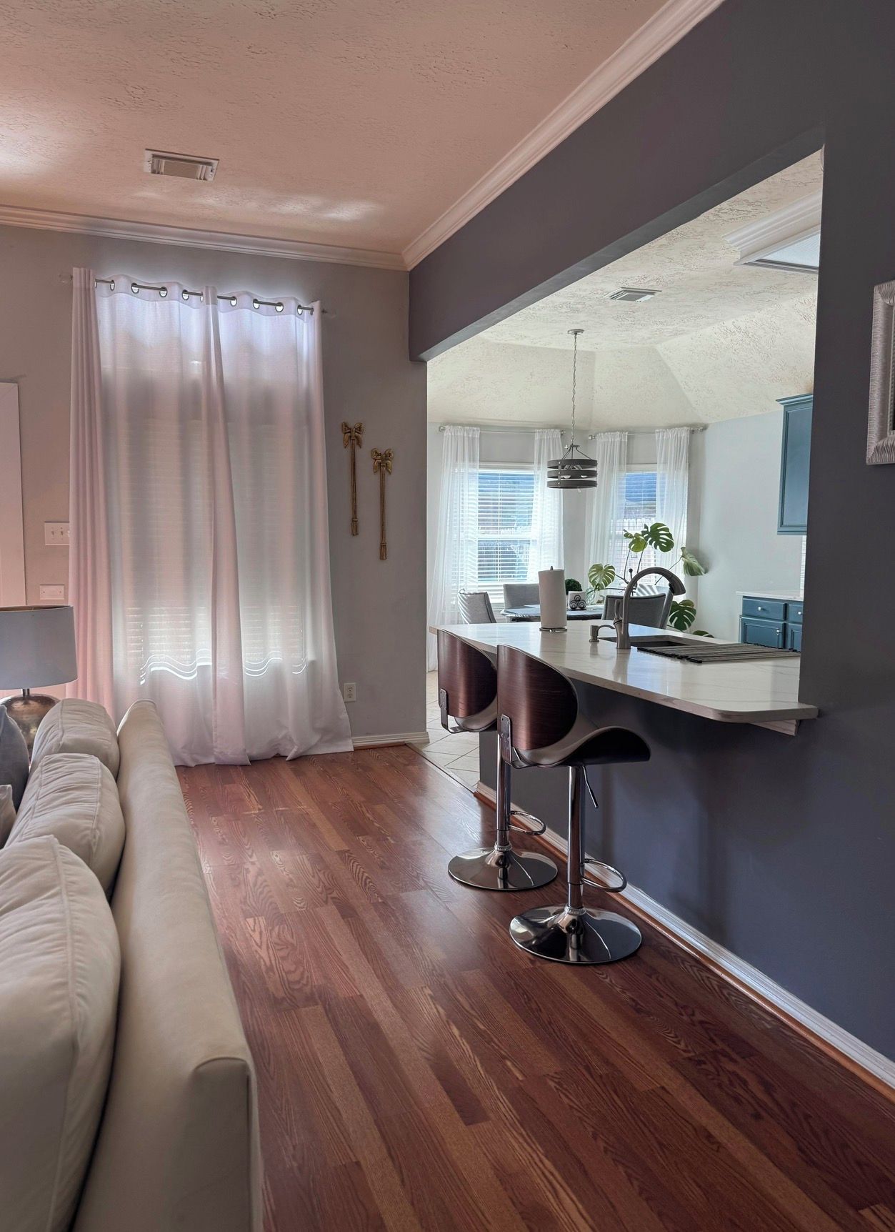Un salon moderne avec un canapé, un coin repas doté d’un tabouret de bar et un grand miroir qui reflète la pièce.