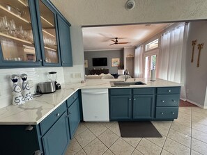 A kitchen with a large island, blue cabinets, and a dishwasher.