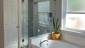 A bathroom with a glass shower enclosure, a white bathtub, and a window. - House of blue! Beautiful pool, near IAH airport (Humble)
