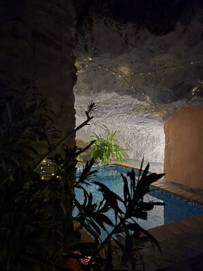 An indoor pool with a tiled edge, surrounded by plants and a cave-like interior with string lights. - Truly unique and authentic town house with cave pool! Lovely mountain village. (Guájar-Faragüit)