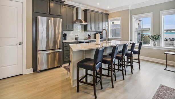 A modern kitchen with a central island, stainless steel appliances, and a view of the outdoors. - Waterfront Condo w/ Rooftop Deck & Beach Access (Fenwick Island)