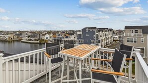 A waterfront deck with outdoor seating, overlooking a residential area and a body of water. - Waterfront Condo w/ Rooftop Deck & Beach Access (Fenwick Island)