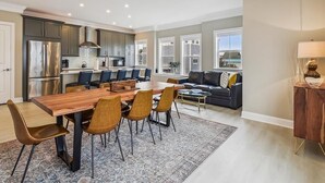 A modern kitchen with a dining area, a living room with a sofa and coffee table, and a view of a pool. - Waterfront Condo w/ Rooftop Deck & Beach Access (Fenwick Island)