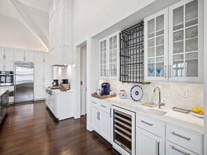 A modern kitchen with white cabinetry, stainless steel appliances, and a large island.