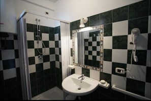 Bathroom with a checkered tile pattern, featuring a sink, handheld showerhead, and mirror.