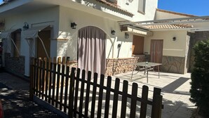 Una casa con un patio, una recinzione in legno e un muro in pietra.