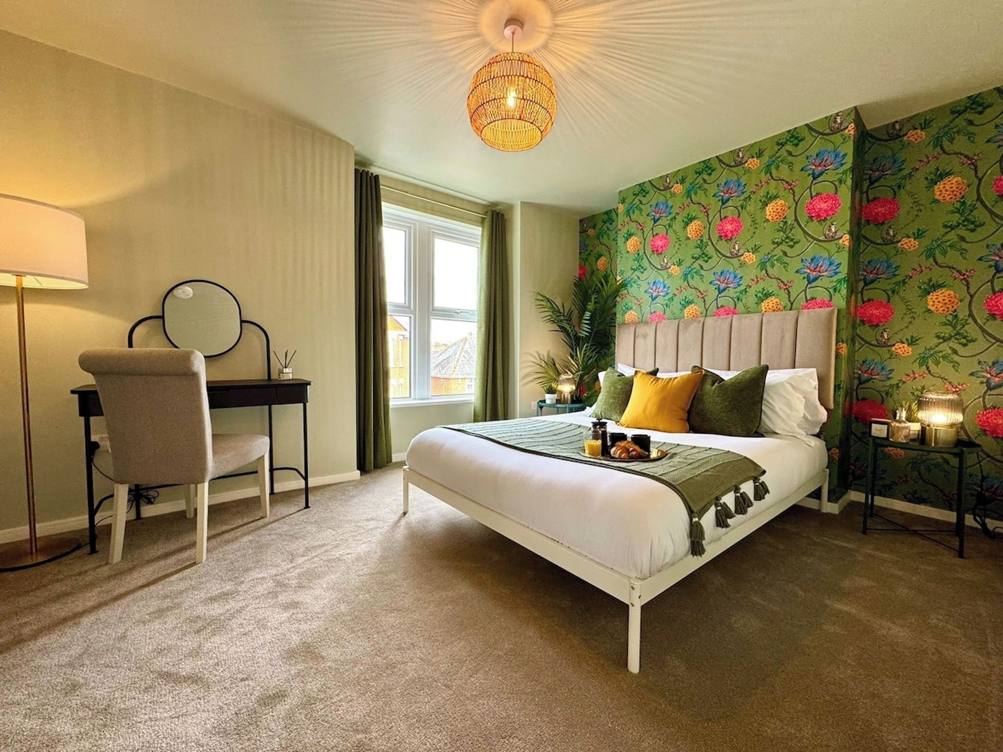 Hotelkamer met een bed, bureau, stoel, spiegel, raam en decoratieve wand.
