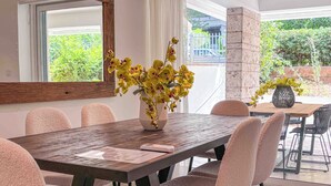 A dining area with a wooden table, chairs, and a vase of yellow flowers. - Elegant Flat in the Center of Glyfada (Glifada)