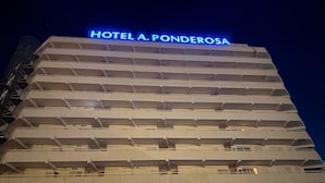 Un immeuble abritant un hôtel à plusieurs étages, sur lequel on peut lire l’inscription « HÔTEL A. PONDEROSA » en haut.