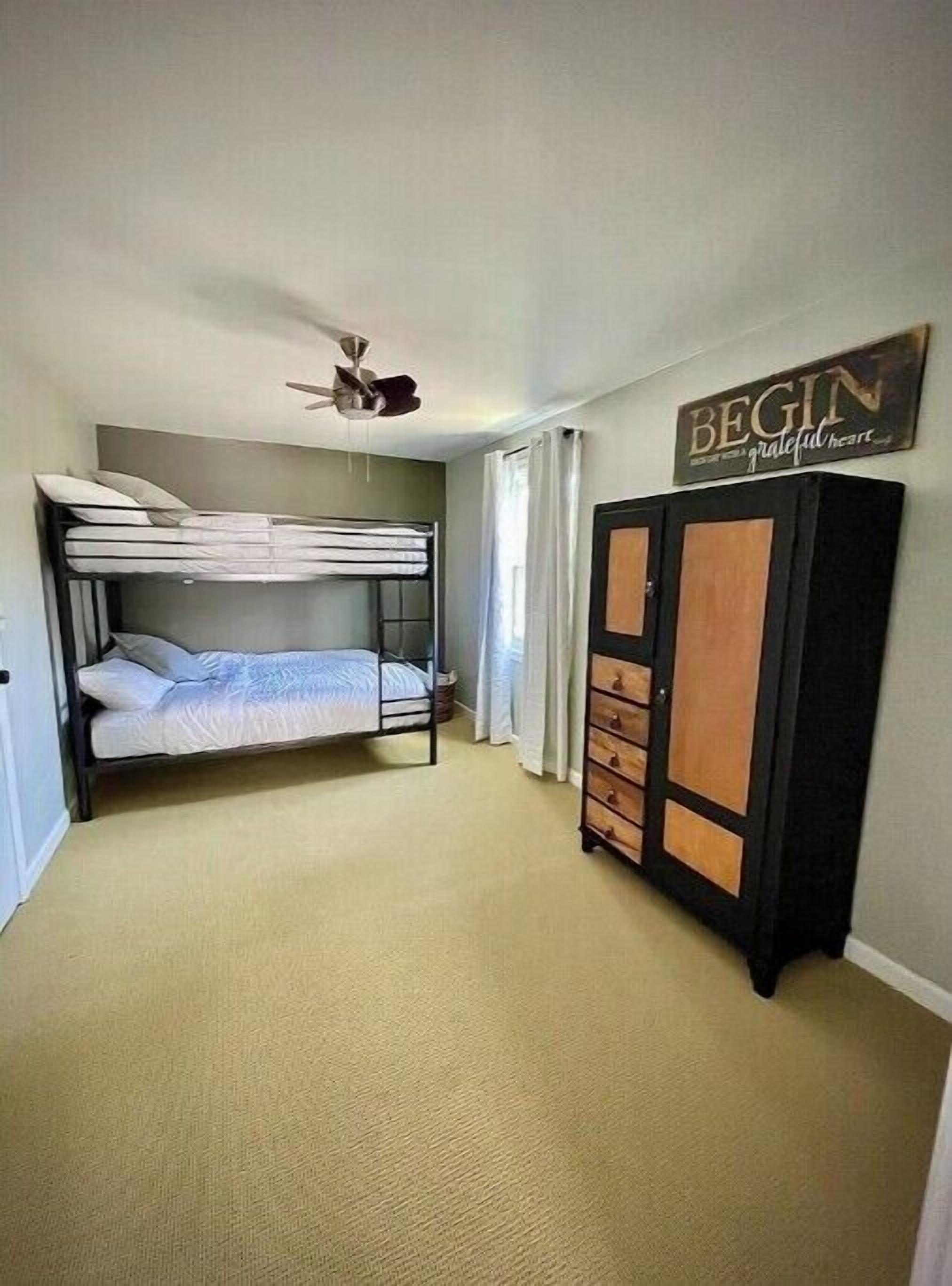 A room with bunk beds, a wardrobe, and a ceiling fan.