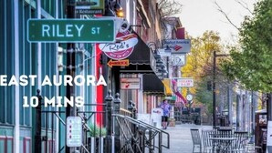 Une vue de rue avec un panneau indiquant « Riley St » et « East Aurora, 10 minutes ».