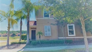 A two-story house with a beige exterior, a front door, and a small window.