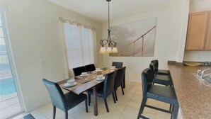 A dining area with a table set for four, a chandelier, and a view of the outdoors.