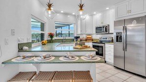 A modern kitchen with white cabinets, stainless steel appliances, and a large island with seating.