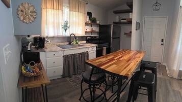 Cocina compacta con una isla de madera, taburetes de bar y un refrigerador.
