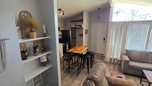 Un espace de vie moderne comprenant un canapé marron, une table à manger en bois et un coin cuisine.