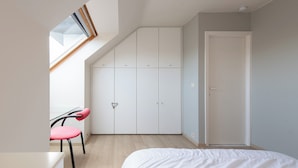 Une chambre à coucher comprenant un lit, un bureau, une chaise, une armoire et une fenêtre de toit.
