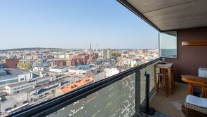 A balcony with a city view, a wooden table, and a chair.