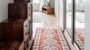 A spacious hallway with a wooden dresser, a patterned rug, and a large sliding glass door leading to another room.