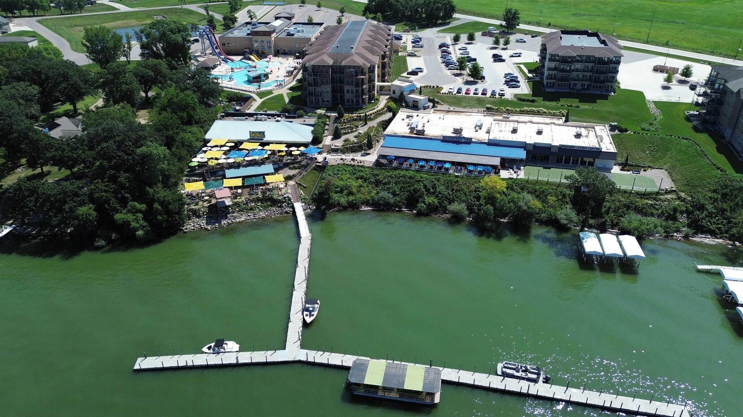 An aerial view of a hotel with a swimming pool, a dock, and a parking area.