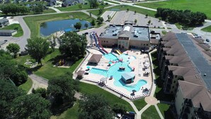 An aerial view of a resort with a large pool, water slides, and a parking area.