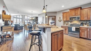 A spacious kitchen with wooden cabinets, a central island, and a dining area with chairs.
