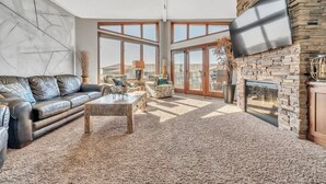A spacious living room with a leather sofa, a coffee table, and a fireplace.