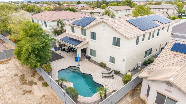 Ein Wohnhaus mit Schwimmbad, Solaranlage auf dem Dach und einer Terrassenfläche.