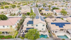 Ein Wohngebiet mit Häusern, die Solarpanels, einen Pool und einen gepflegten Rasen haben.