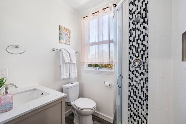 A bathroom with a shower, toilet, and sink.