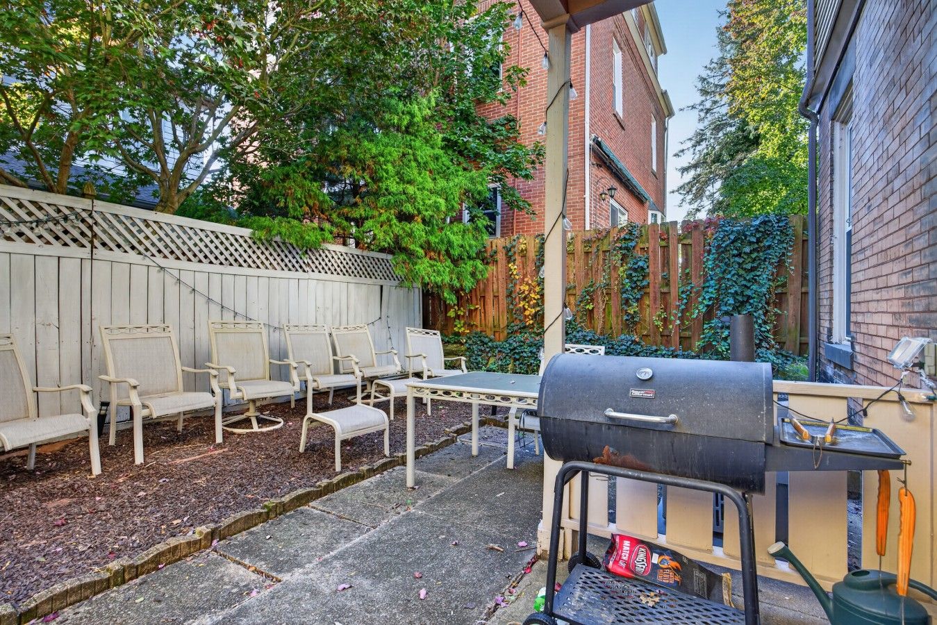 A backyard with a barbecue grill, outdoor furniture, and a wooden fence.