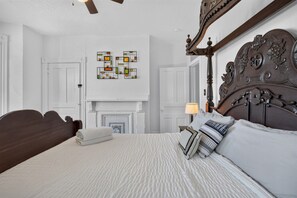 A bedroom with a large bed, a fireplace, and a wall art piece.