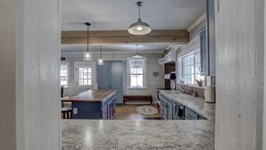 A kitchen with granite countertops, pendant lighting, and a wooden ceiling beam. - Sleeps 29!  9-bedroom 8-Bath 3-Kitchen, Historic McBride Farm in Garden Valley (Garden Valley)